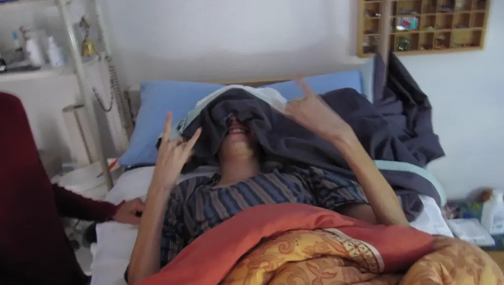 stay heavy: Jonas macht im Pflegebett die Pommes-Gabel und grinst